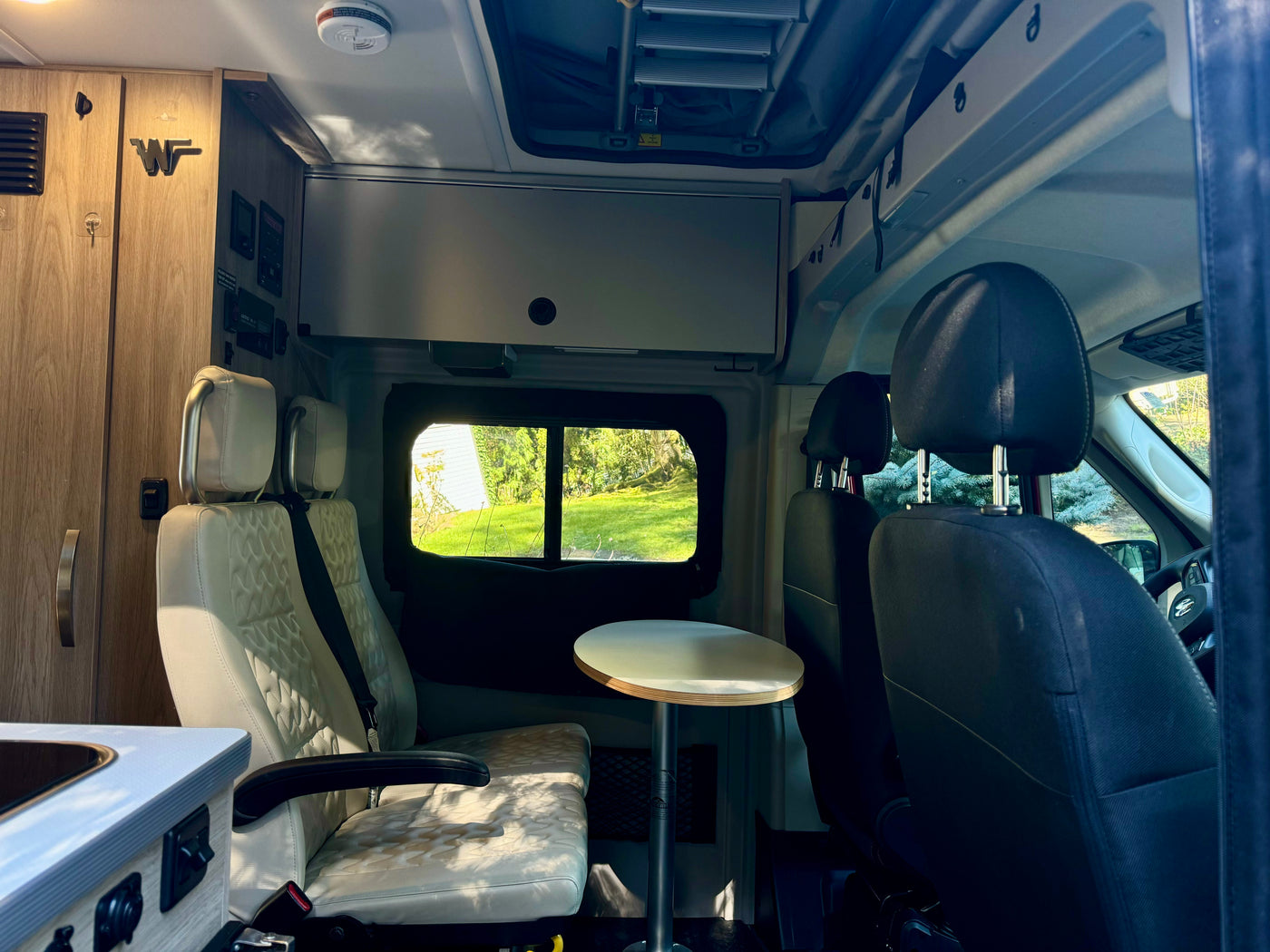 Bright RV rental interior with comfortable swivel seating, dining table, storage, and a scenic outdoor view. — photo 5