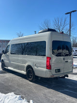 Light grey Mercedes Sprinter RV rental camper van parked in a snowy lot on a sunny day.
