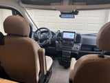 RV rental interior: RAM cockpit with large infotainment screen, steering wheel, and beige leather driver's seat.