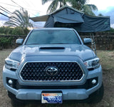 Front of a grey Toyota Tacoma pickup truck, equipped with a Nomadic rooftop tent, ideal as an RV rental in Hawaii.