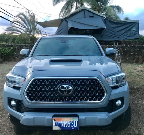 Front of a grey Toyota Tacoma pickup truck, equipped with a Nomadic rooftop tent, ideal as an RV rental in Hawaii.