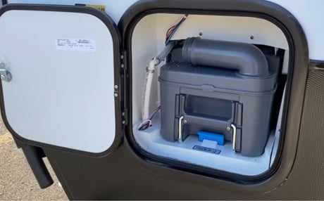 RV rental: External compartment open, revealing a gray cassette toilet for waste disposal and maintenance.