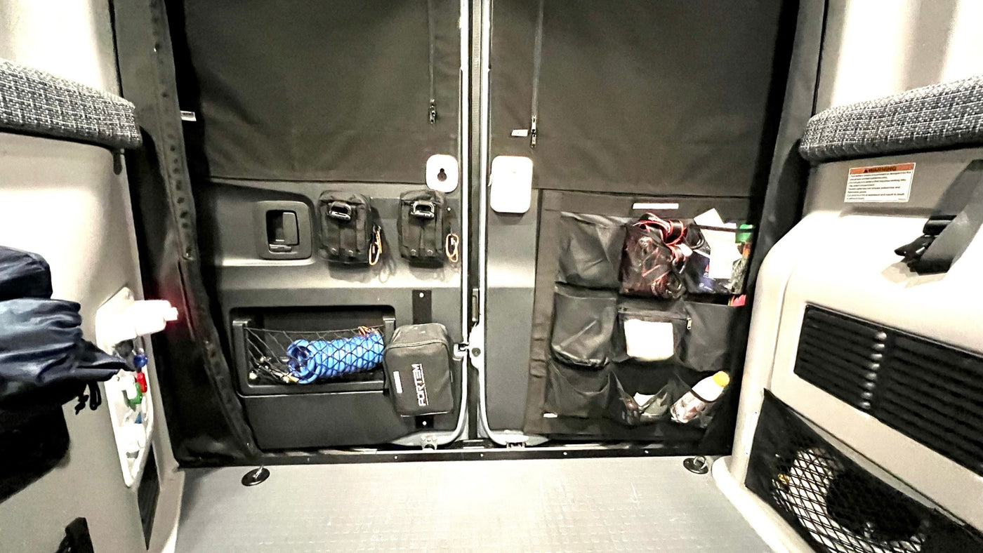 RV rental interior: organized rear doors with blackout shades. Various storage includes tactical pouches, nets, and multi-pocket organizers. — photo 3