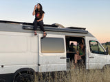 Enjoying an RV rental: Two women relax, one on the roof, one inside, with drinks in their camper van.