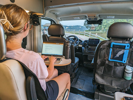Working remotely in an RV rental! This image shows a person on a laptop inside a camper van, a mobile office setup with outdoor views.
