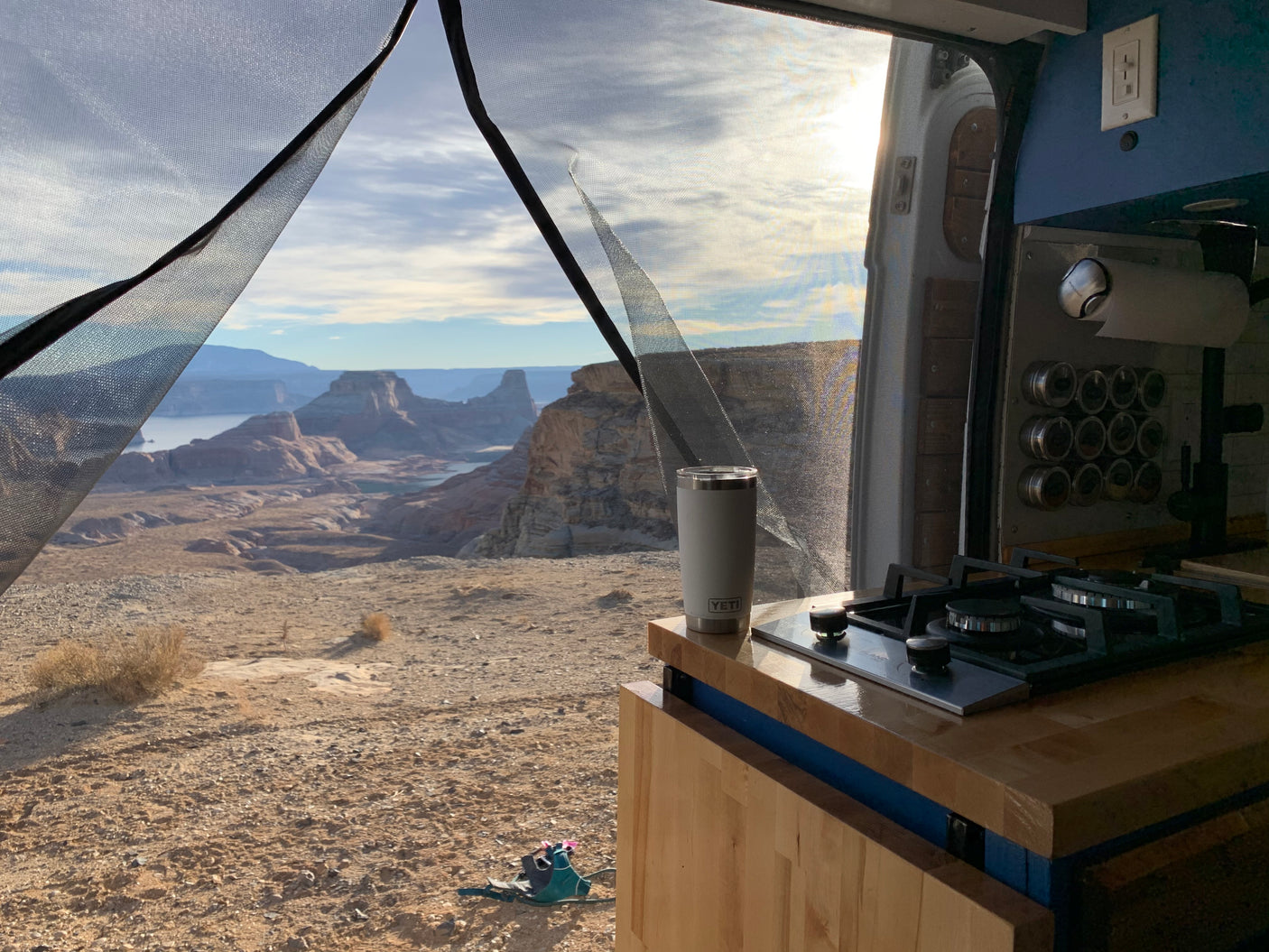 Panoramic desert and lake view from an RV rental van, featuring an interior kitchen. Ideal for van life adventures.