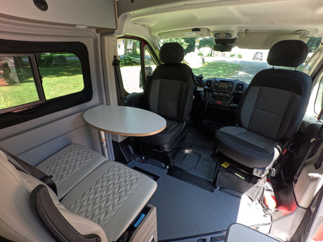 Inside this RV rental: A well-appointed camper van interior with front seats, dining table, and cozy bench seating.
