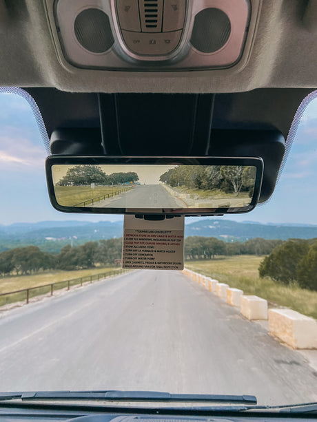 Inside an RV rental, a departure checklist hangs by the rearview mirror, outlining steps for a smooth send-off.
