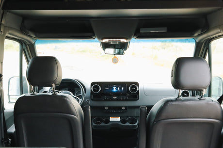 Inside an RV rental: a clear front cabin view with the dashboard, steering wheel, and infotainment screen. Ready for your road trip!