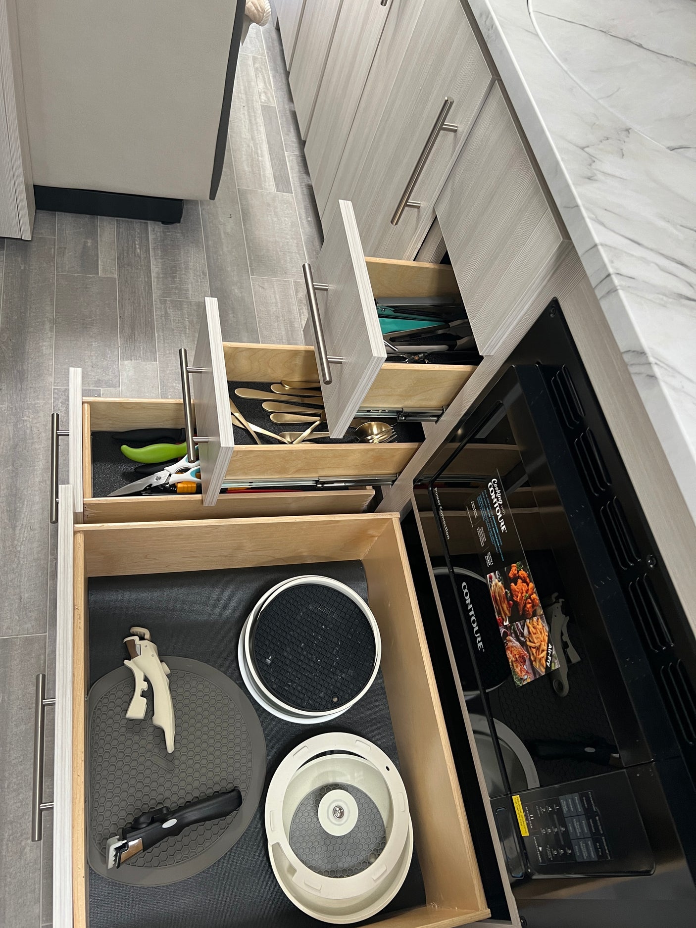 RV rental kitchen: Organized drawers reveal utensils, flatware, and cooking tools beside a convection oven.