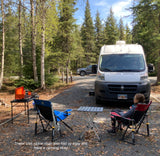 Enjoying a peaceful RV rental campsite setup with comfortable rocker chairs and an outdoor cooking station amidst the trees.
