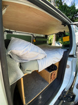Cozy RV rental interior: bed, wood paneling, and built-in storage. Ideal for road trip adventures.