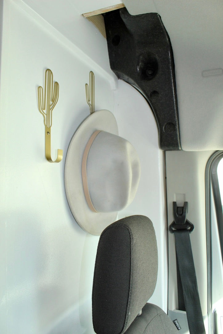 Stylish cactus hooks hold a hat in this organized RV rental interior, perfect for travel storage.