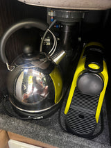 RV rental compact kitchen setup: sleek electric kettle & bright yellow Nespresso machine for your morning brew.