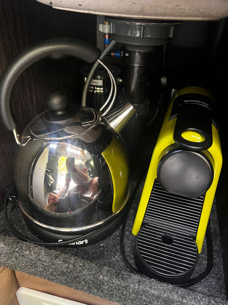 RV rental compact kitchen setup: sleek electric kettle & bright yellow Nespresso machine for your morning brew.