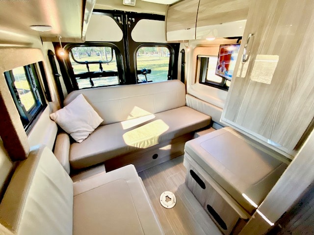  offering outdoor views.|This RV rental interior shows a cozy bed next to a kitchenette with a sink — photo 10