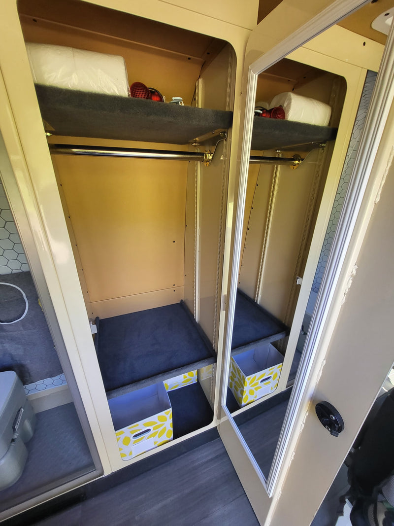  and a table. A white dog waits outside the open back doors.|Step into this RV rental: a practical van life setup with wood counters — photo 11