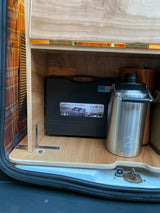 RV rental storage compartment with a Gas One portable stove and an insulated thermos for camping.