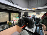Cozy RV rental interior: making coffee in a camper van kitchen with a pop-top roof and nature view.