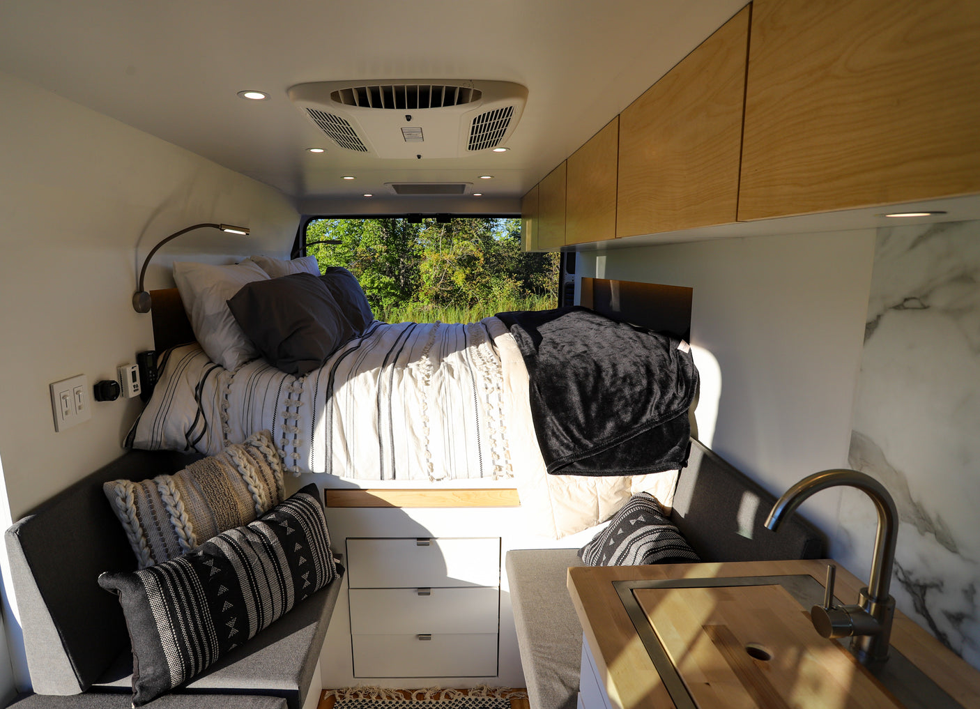 This RV rental's modern interior boasts a comfy bed, compact kitchen, and stylish seating, perfect for your next adventure.