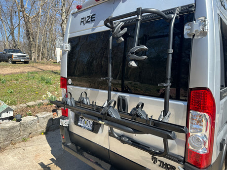 Rear view of a silver Thor Rize RV rental camper van, equipped with a Thule bike rack, ready for adventure.