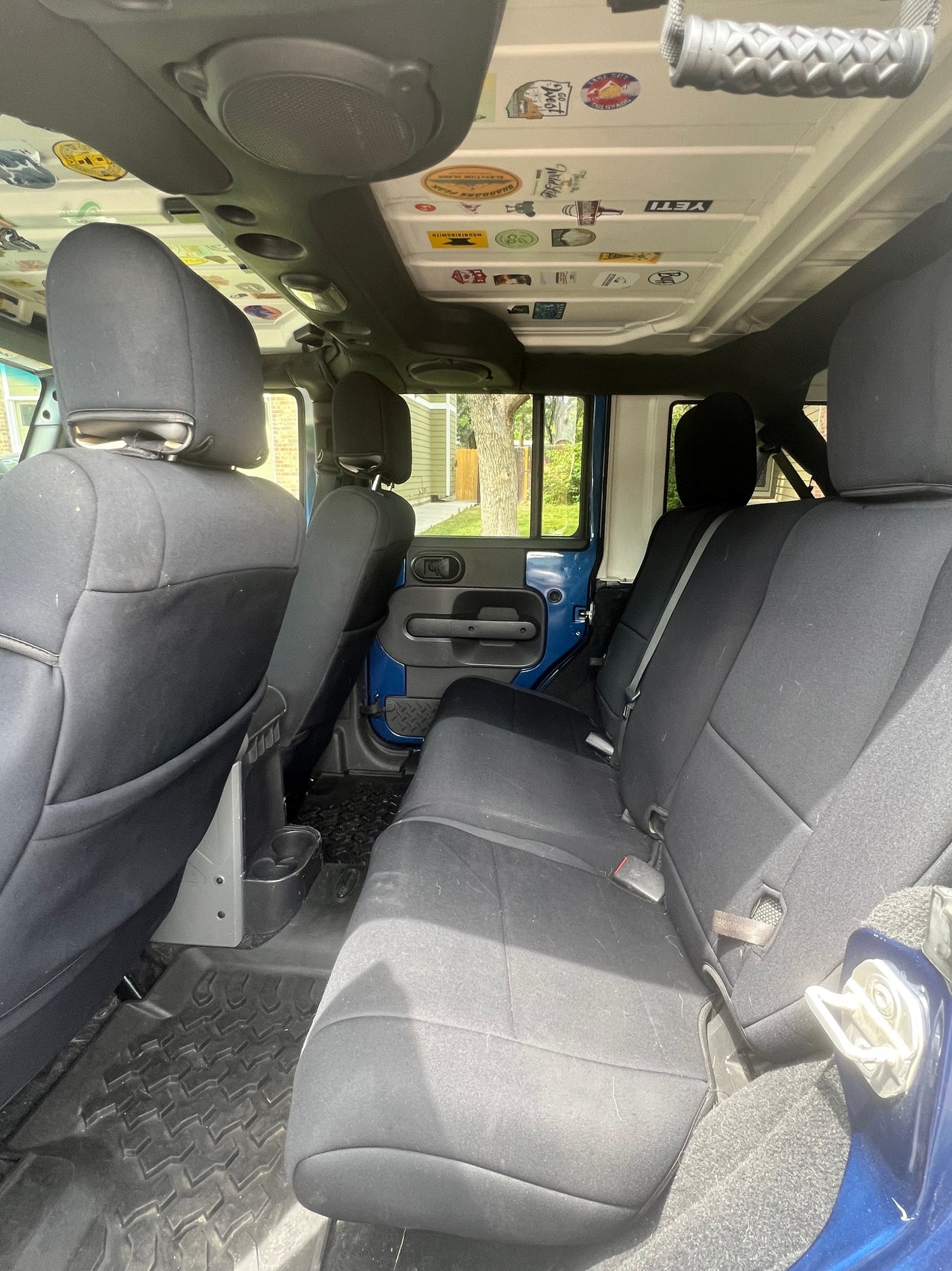 Jeep interior showing rear cloth seats, rugged rubber mats, and a custom sticker-covered ceiling. A versatile alternative to an rv rental.