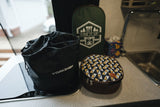 RV rental ready: Black YORKENBE bag, green "Fire It Up" pouch, and patterned round zippered case on a camper counter.