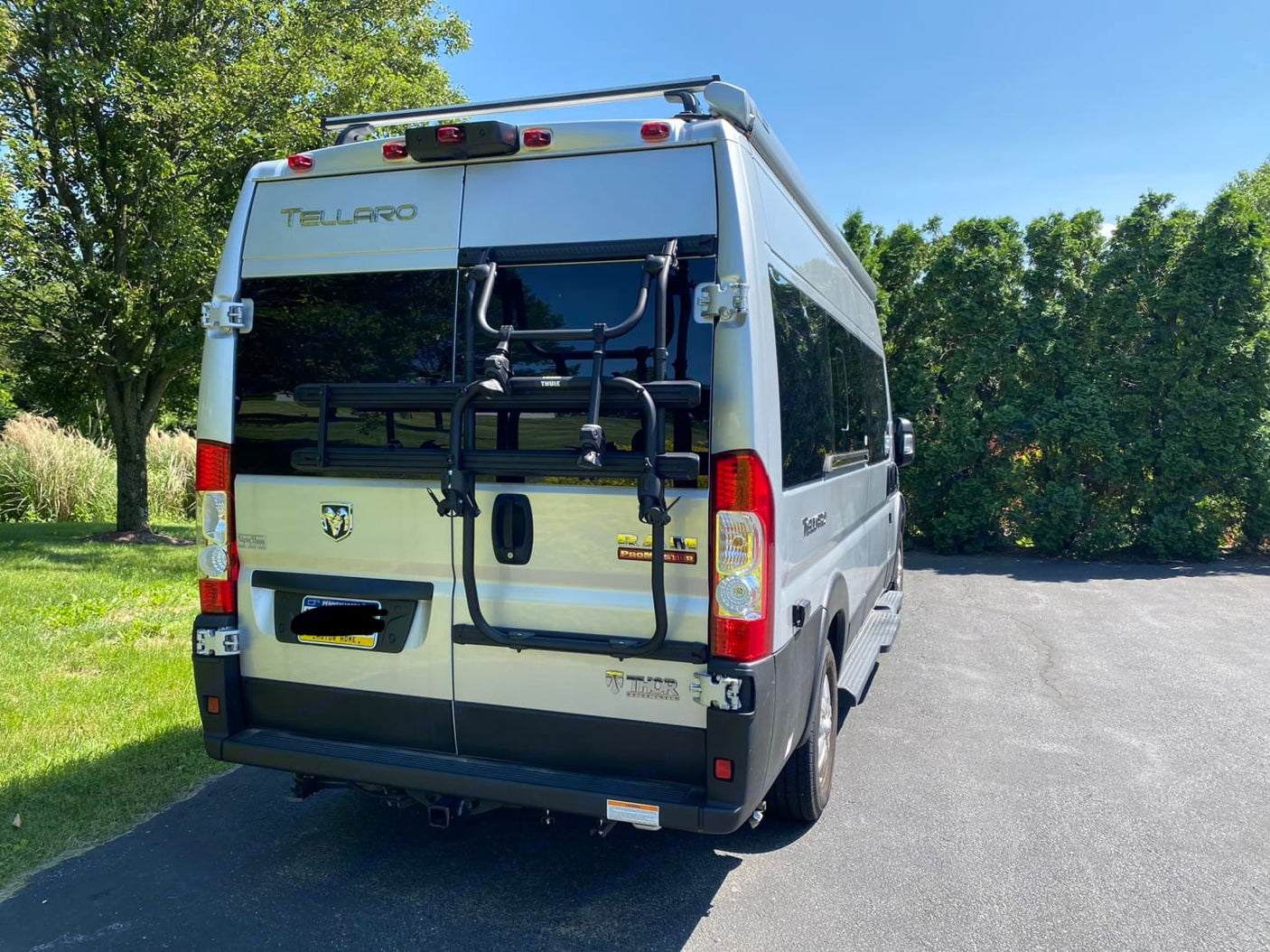 Rear view of a shiny silver Thor Tellaro camper van equipped with a Thule bike rack, perfect for your next rv rental trip.