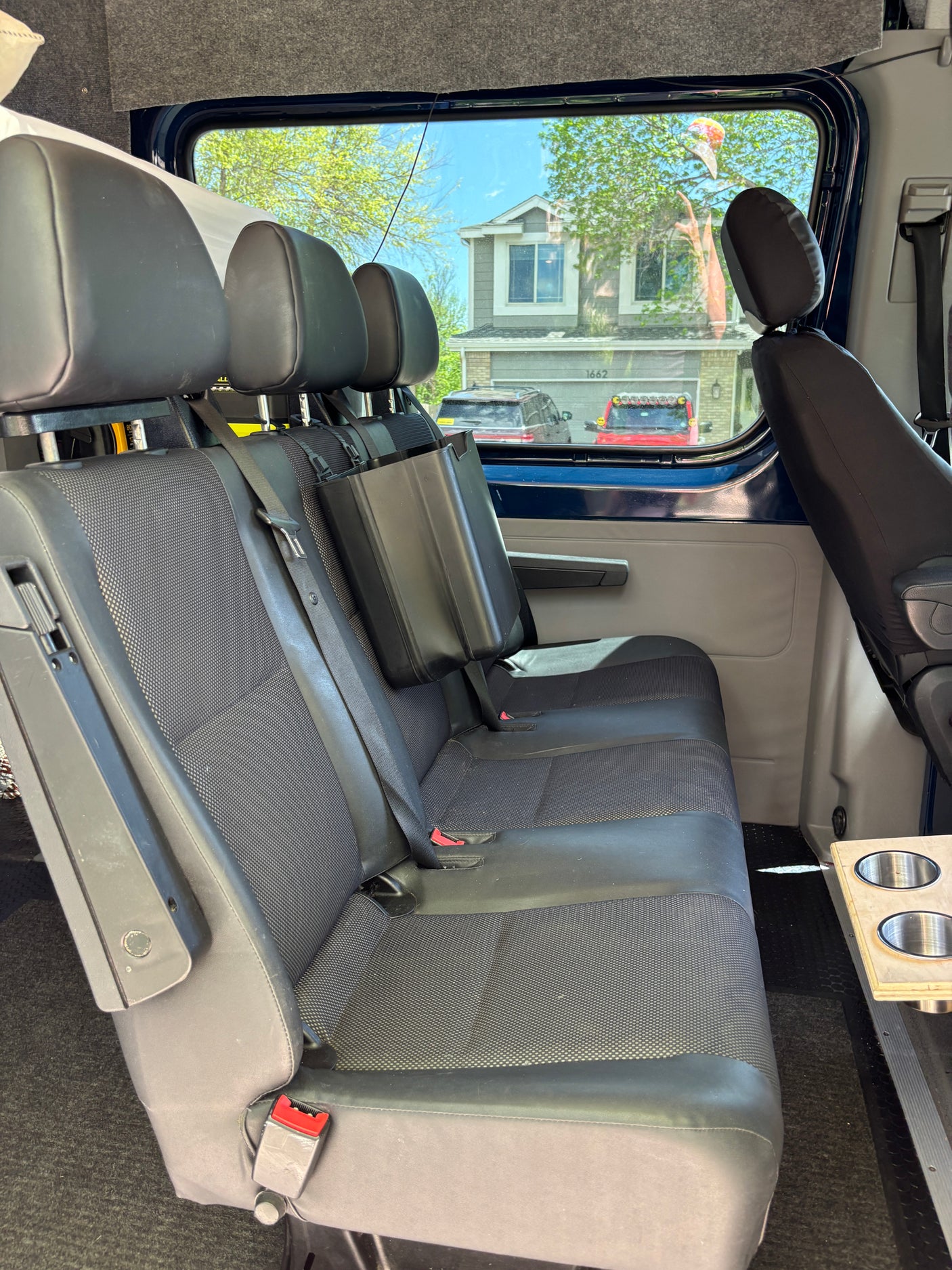 RV rental: View of comfortable rear seating in a camper van interior, featuring handy cup holders.