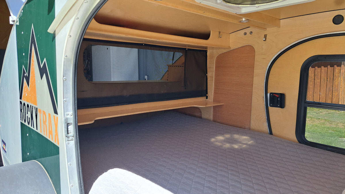 Inside a compact rv rental: a comfy bed, wooden storage, and screens on windows for a cozy travel experience. — photo 11