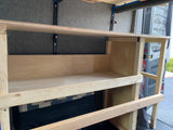Custom wooden shelving inside an RV rental van, offering practical storage solutions in the built-out interior.