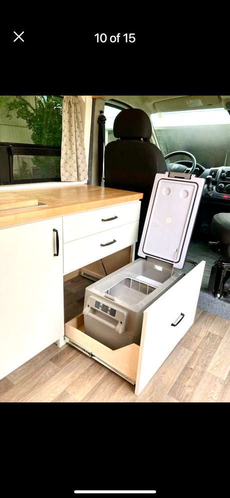 RV rental interior: organized kitchen with pull-out fridge/freezer, light wood counter, and white cabinets.