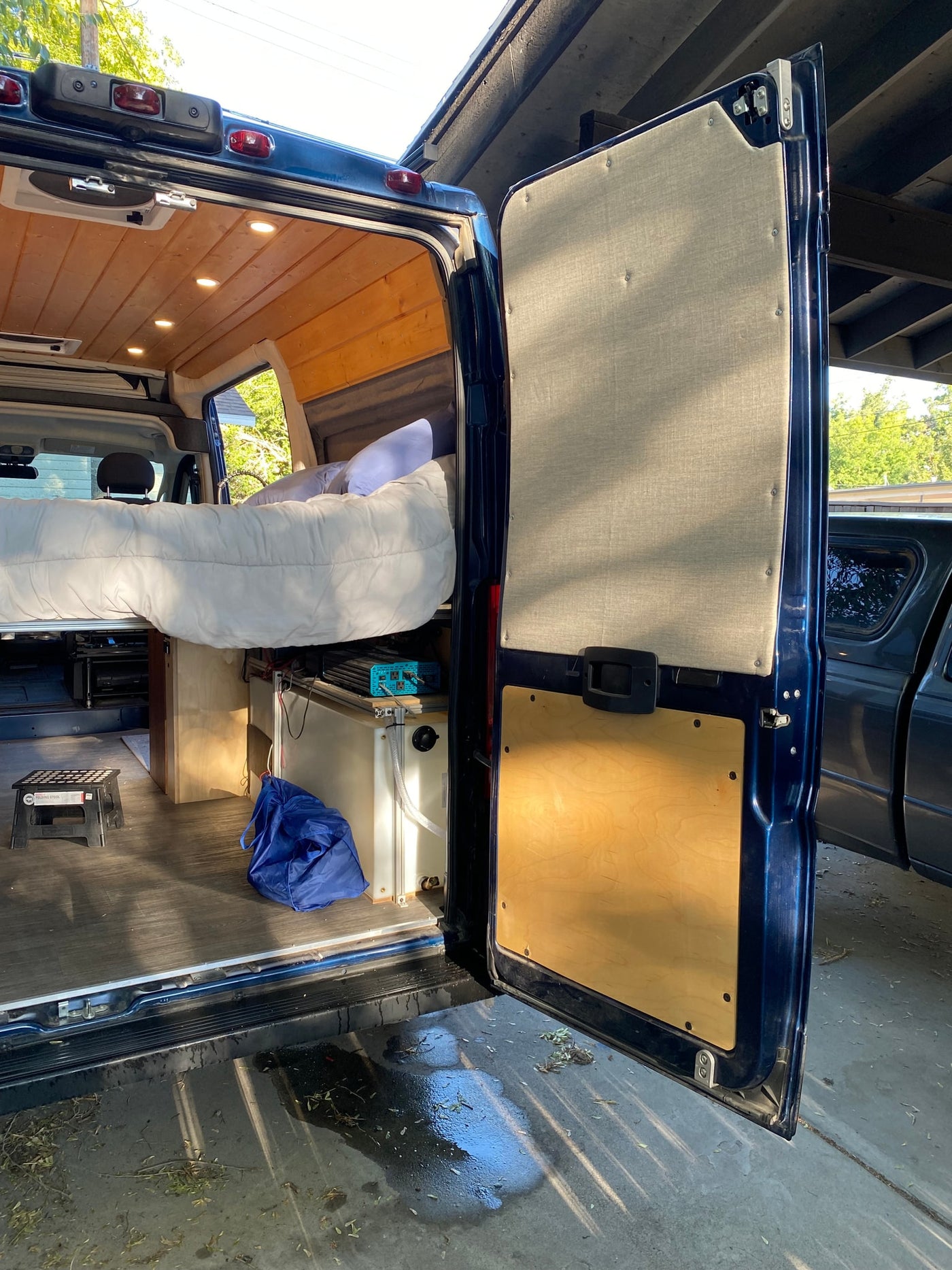 Step into this custom camper van RV rental! Features a cozy raised bed, wood ceiling, & organized utilities. — photo 4