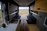 Experience a spacious RV rental: complete with a functional kitchen, dining benches, storage, and scenic rear views.