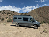 Explore the wilderness with this rugged Sprinter adventure rv rental van, parked in arid, mountainous terrain.