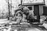 A dad and his three smiling kids at an RV rental campsite enjoying an outdoor meal together.
