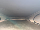 Interior of an RV rental pop-top camper: raised fabric roof, bed, and ceiling lights, providing a comfortable sleeping space.