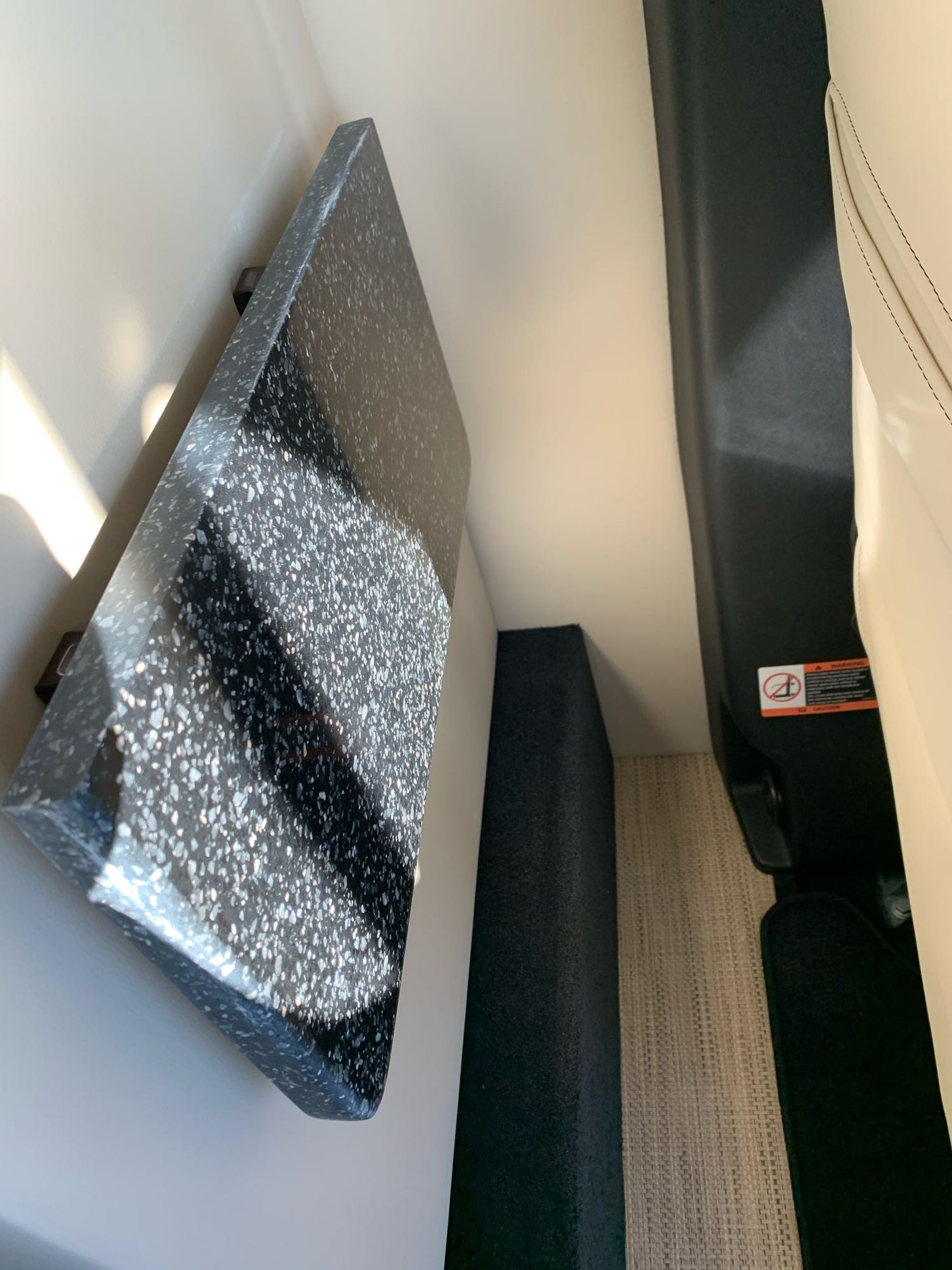 Inside an RV rental: dark speckled counter, light seating, and woven floor mat. Functional, compact vehicle interior.