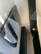 Inside an RV rental: dark speckled counter, light seating, and woven floor mat. Functional, compact vehicle interior.