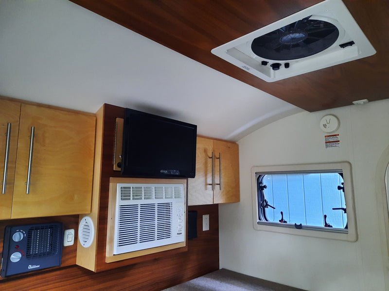 A well-equipped RV rental interior featuring wood cabinets, TV, AC unit, and ceiling fan for your adventure. — photo 6