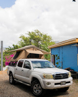 White Toyota truck with a rooftop tent, a versatile RV rental for Hawaii camping adventures.