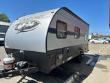 A sleek gray Wolf Pup travel trailer, ideal for your next RV rental adventure. Parked outside on asphalt.