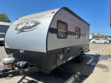 A sleek gray Wolf Pup travel trailer, ideal for your next RV rental adventure. Parked outside on asphalt.