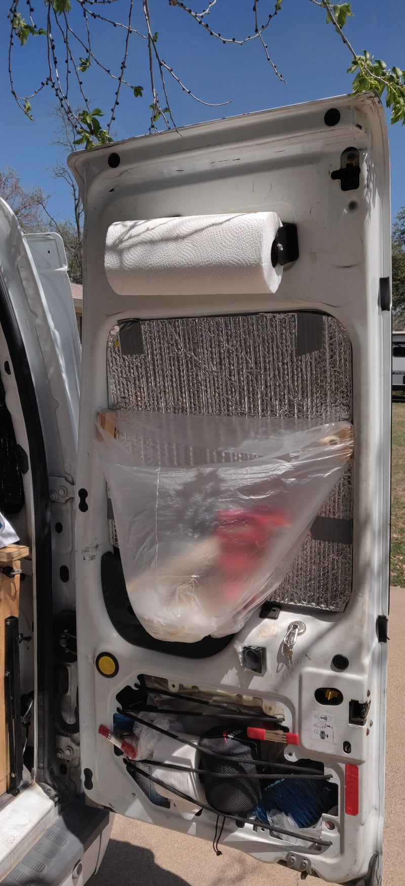 Organized RV rental van door features paper towels, insulation, hanging bag, and bungee tool storage for travel. — photo 14