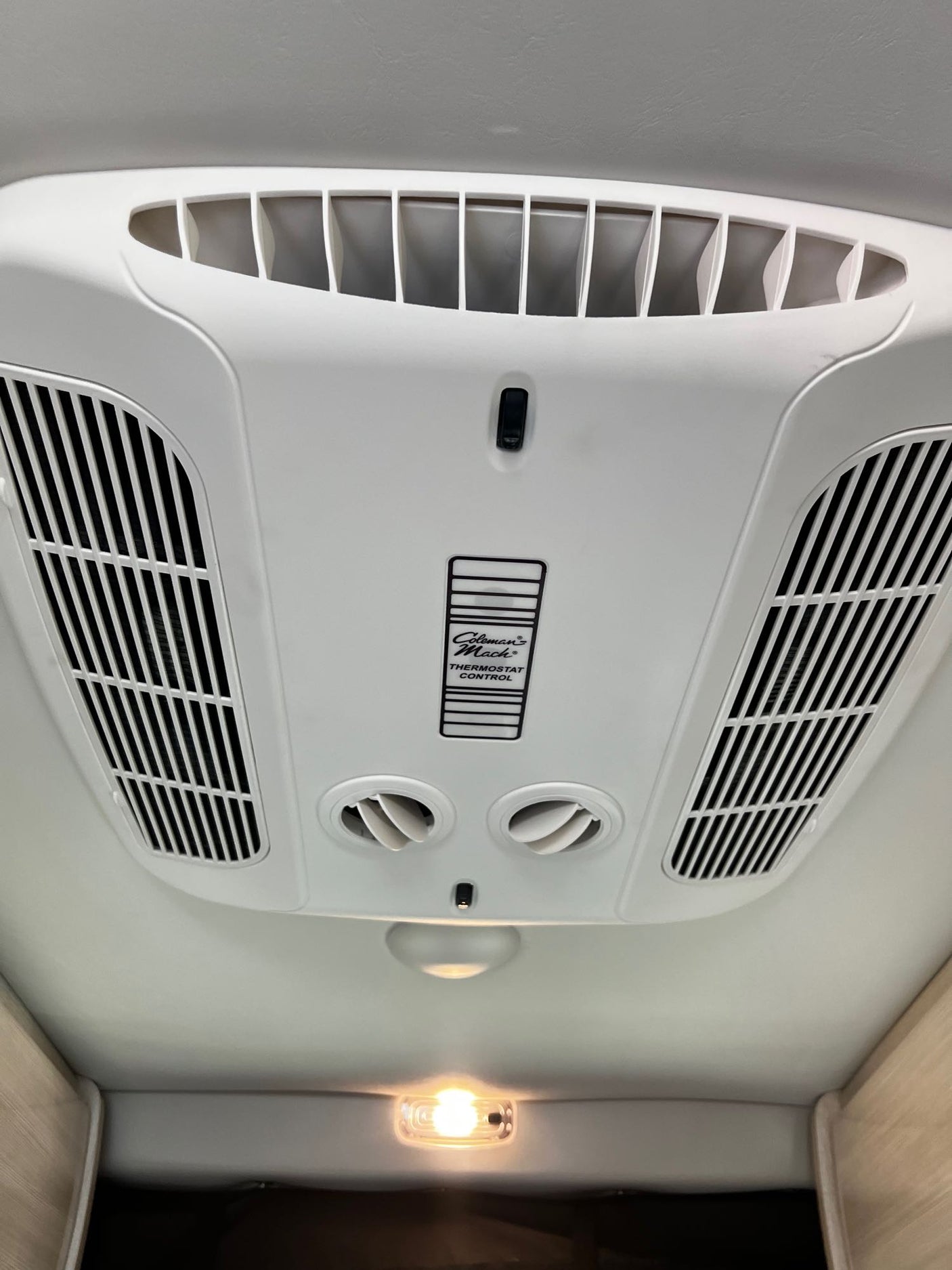 RV rental: Ceiling-mounted Coleman Mach AC and climate control unit with air vents and a light.