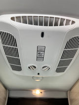 RV rental: Ceiling-mounted Coleman Mach AC and climate control unit with air vents and a light.