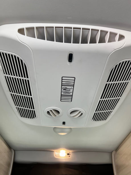 RV rental: Ceiling-mounted Coleman Mach AC and climate control unit with air vents and a light.