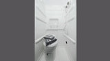 Functional RV rental wet bath. Features a compact toilet with folded towels, a shower, and an integrated shelf.
