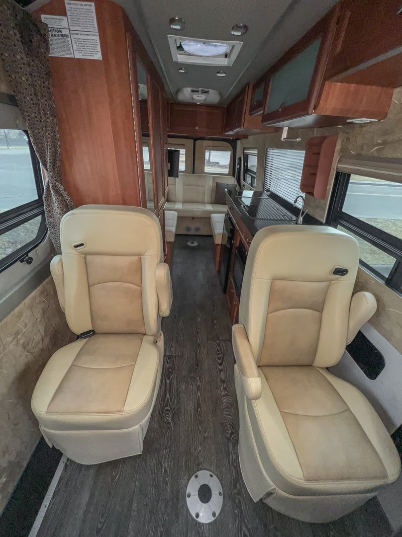 Spacious RV rental interior features front swivel seats, galley kitchen, and rear lounge area. — photo 9