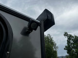 Cloudy sky over an RV rental. Side view shows a dark gray panel, black LED light, and a black zippered awning cover on the roof.